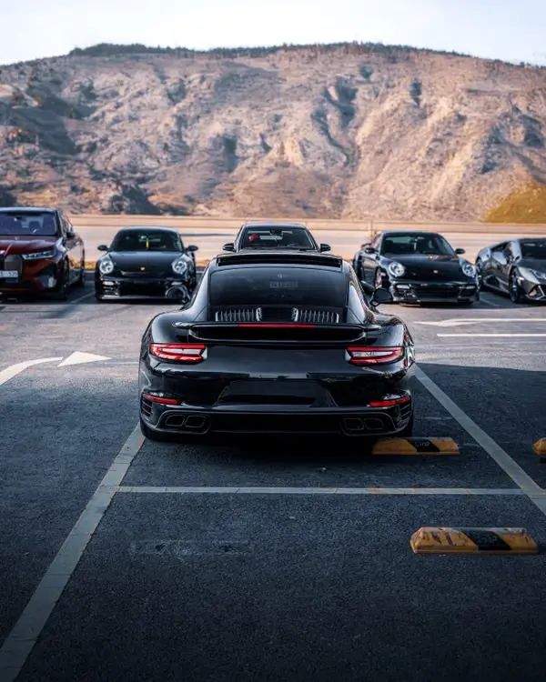 Zwarte Porsche 911 Turbo met andere sportwagens op de achtergrond